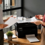 Karyawan sedang menggunakan printer multifungsi di kantor modern sebagai ilustrasi Managed Print Services (MPS) untuk meningkatkan efisiensi operasional dan mengurangi biaya cetak perusahaan.