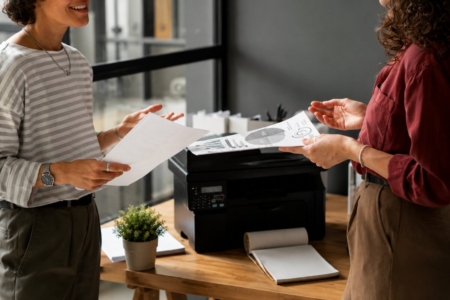 Karyawan sedang menggunakan printer multifungsi di kantor modern sebagai ilustrasi Managed Print Services (MPS) untuk meningkatkan efisiensi operasional dan mengurangi biaya cetak perusahaan.